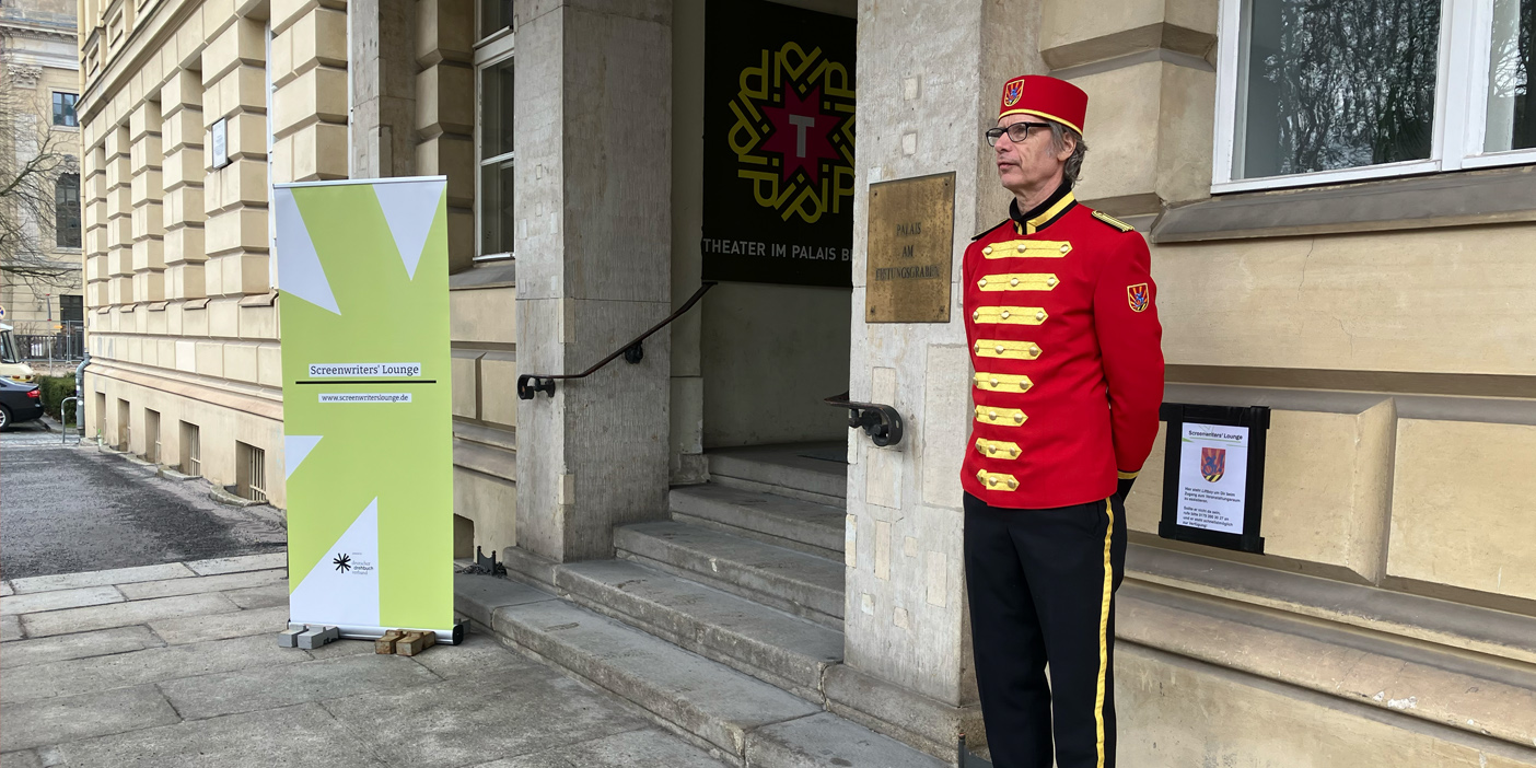 Ein Mann in Liftboy-Uniform steht neben der Treppe im EIngang des "Theater im Palais", Berlin